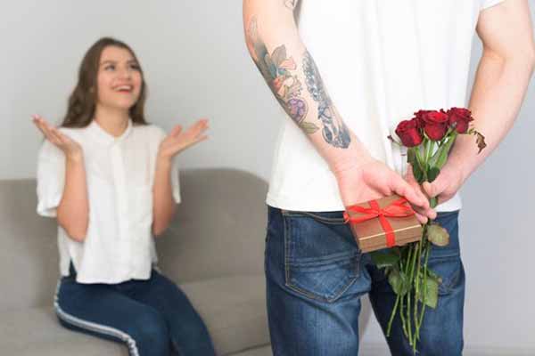 чоловік дарує дружині квіти та подарунок