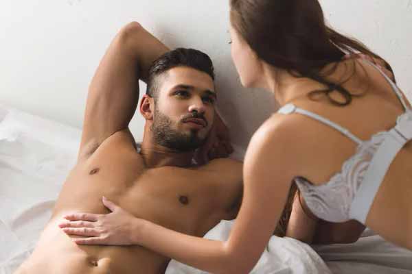 Страстный мужчина целует красивую женщину в постели